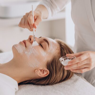 Cosmetologist doing face treatment and applying face mask